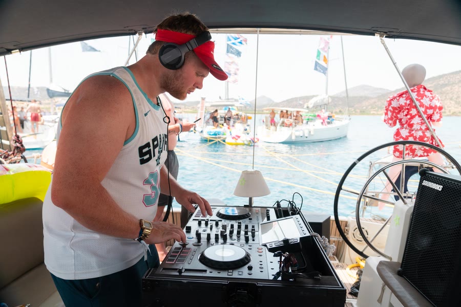 A DJ playing from the back of a yacht, the rafted fleet behind